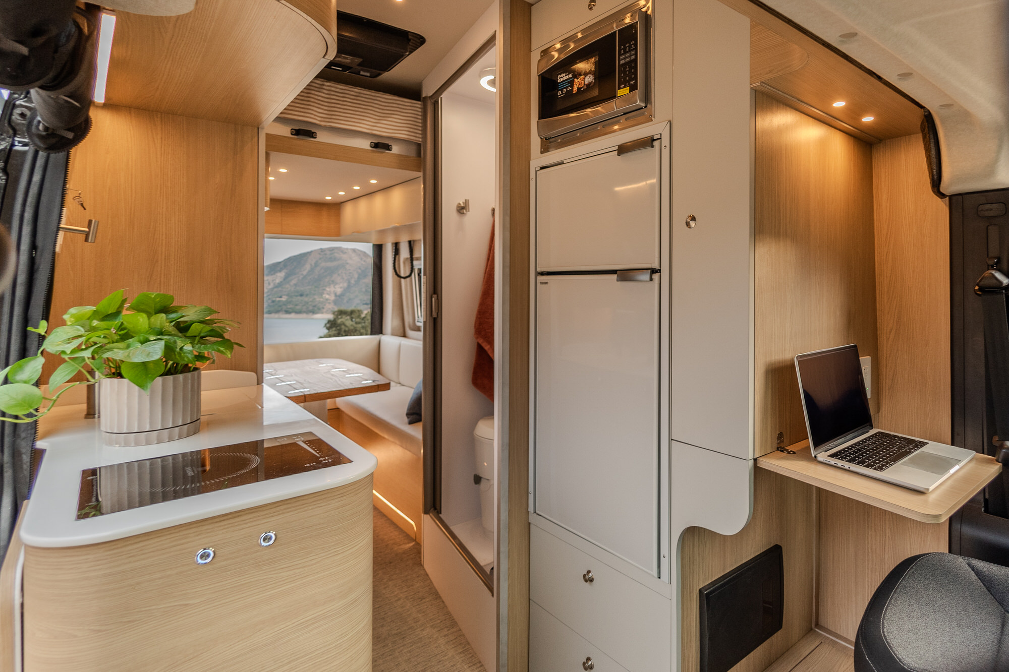 2025 Noovo Plus luxury camper van interior - featuring kitchen, workspace, and living area